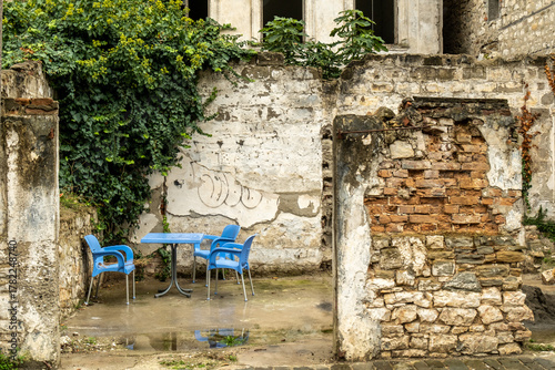 Kleiner Hof mit blauen Stühlen vor verfallener Steinmauer, Berat, Bezirk Berat, Albanien