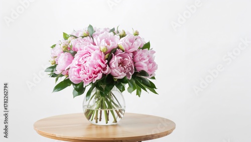Vibrant peony arrangement in a vase on a table, ideal for editorial header background
