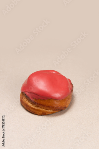 Sweet Bun with Red Cream Frosting on Solid Background
