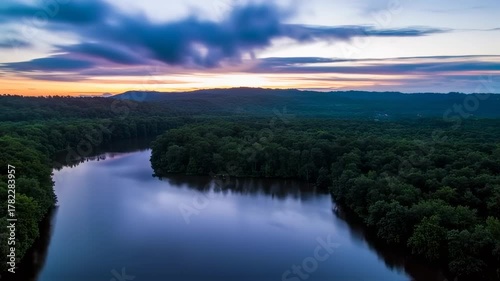 Aerial View of a Serene River Winding Through Lush Green Forests at Sunset.