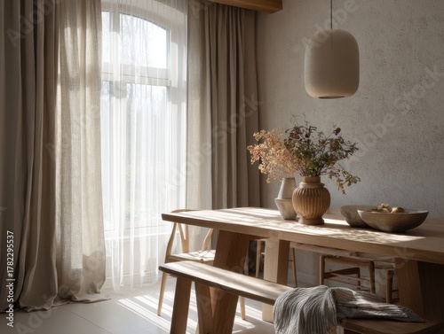 A wooden dining table with a vase of flowers on it. The table is surrounded by chairs and a bench