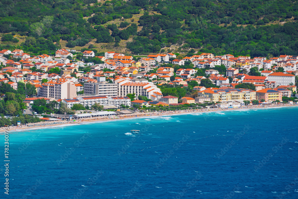 Fototapeta premium Coastal townscape with mountain background and vibrant blue sea. Baška, Krk island, Croatia