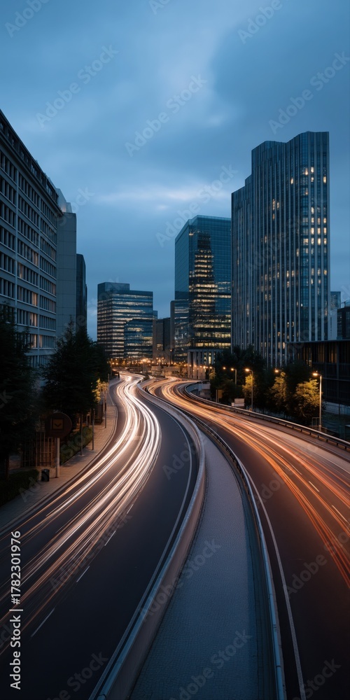Obraz premium Night cityscape with light trails on curved highway and illuminated skyscrapers