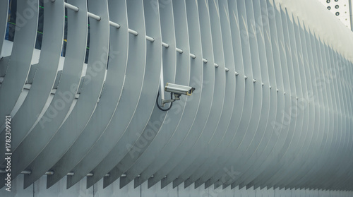 A modern white CCTV security camera mounted outdoors on a building, representing surveillance, protection, and modern technology.