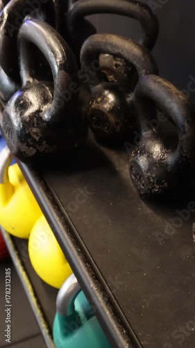 Female hands picking kettlebells in gym, vertical video. Close-up view of female hands lifting kettlebells in gym. Fitness lifestyle concept, workout equipment and body strength preparation 9:16