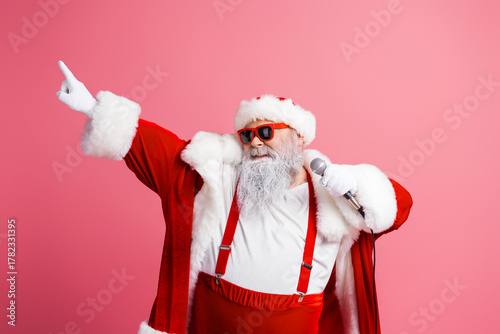 Billede på lærred Santa entertainer singing with microphone in pink studio wearing red costume hat