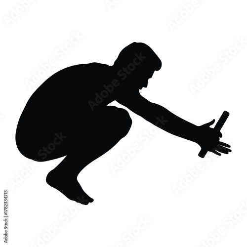 Silhouette of a man crouching and reaching for an object