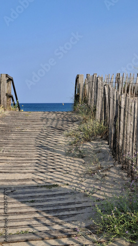 Un chemin en caillebotis en bois menant à la plage des Trois Digues à Sète