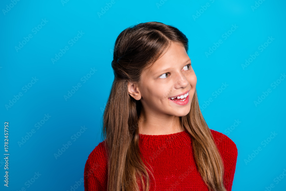 Fototapeta premium Smiling girl in red sweater against blue background captures festive winter mood and joy