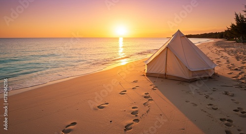 Idyllic beach camping scene featuring a tent at sunrise casting a warm golden glow creating a