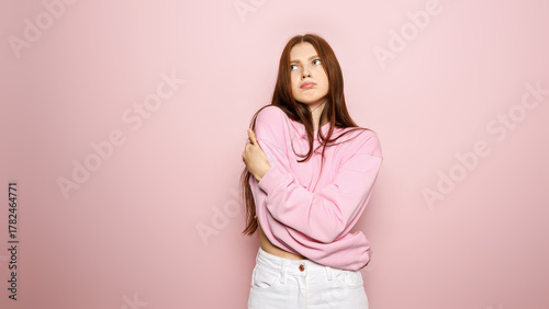 Young Woman in Pink Sweatshirt on Pastel Background