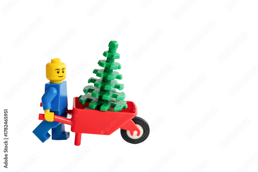 Obraz premium A LEGO man pushes a Christmas tree in a cart.