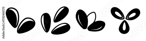 A collection of black seeds or beans scattered on a, with some grouped in pairs and one group of three