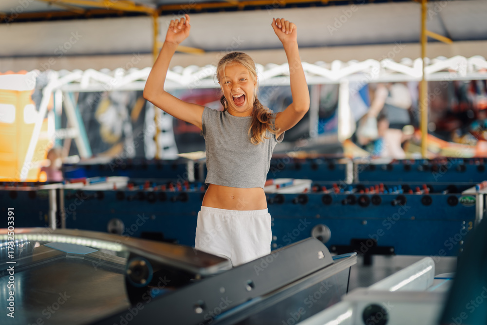 Naklejka premium Excited girl celebrating winning an arcade game at amusement park