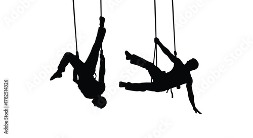 Silhouettes of two people suspended upside down from ropes or cords