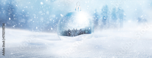 Gläserne WEihnachtskugel mit Wintermotiv in einer Bewaldeten Schneelandschaft