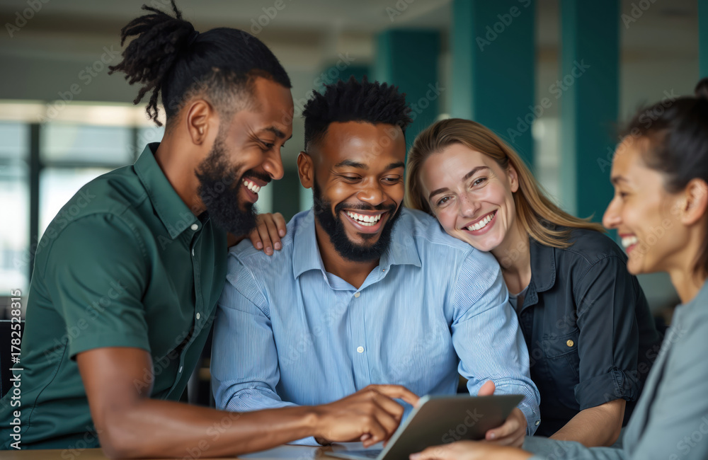 Fototapeta premium Diverse group of smiling business people collaborate around a tablet. Colleagues share ideas and laughter in a modern office setting, enjoying teamwork and a positive work environment.