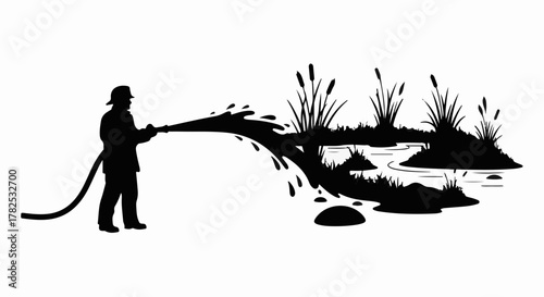 Firefighter uses hose to douse a marshy area with reeds and water