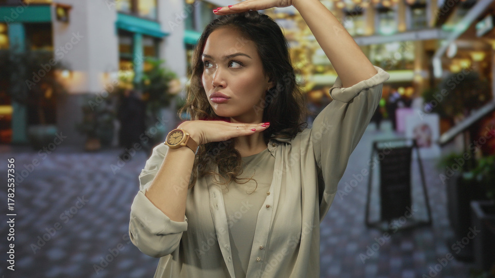 Fototapeta premium Hispanic woman performs framing gesture with hands on bustling street; creativity imagination perspective vision.
