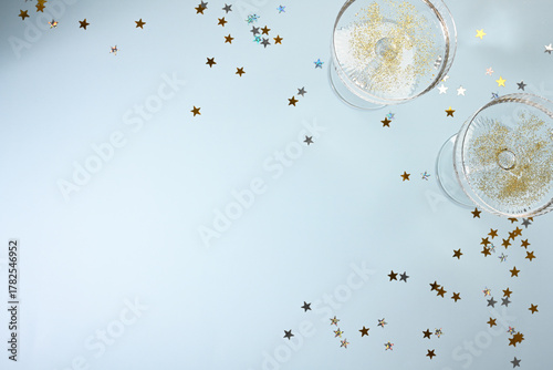 Champagne glasses with golden confetti on blue background