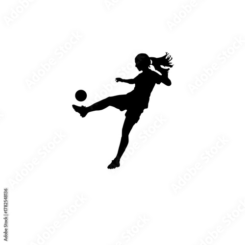 Silhouette of a young girl kicking a soccer ball in mid air with her hair flowing