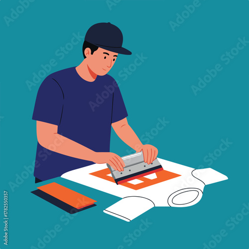 A person with a cap screen printing a design onto a white t-shirt using a squeegee and stencil