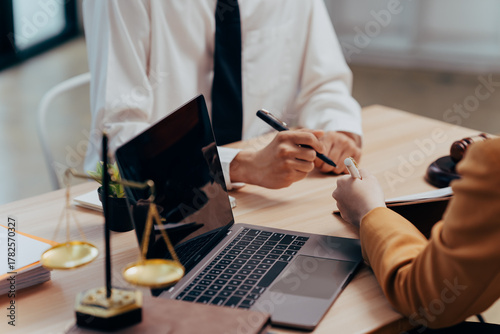 Legal Consultation: A close-up view capturing the atmosphere of legal consultation. A laptop, scales, and documents are arranged on the table, creating a professional environment