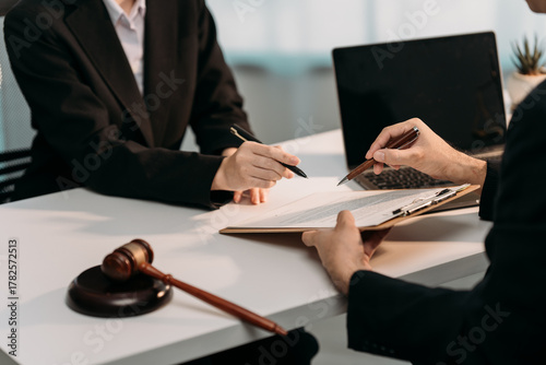 Negotiating Legal Matters: A pair of legal professionals engaged in a crucial signing ceremony, as they navigate the intricacies of a legal agreement.