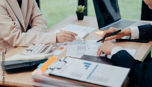 Business discussion in office: Close-up of two individuals engrossed in a focused business discussion over documents in an office environment, showcasing collaboration and productivity. 