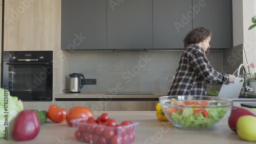 Woman Washing Cutting Board After Preparing Fresh Vegetables In Modern Kitchen