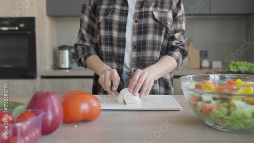 Woman Slicing Mozzarella Cheese On Wooden Board In Modern Kitchen