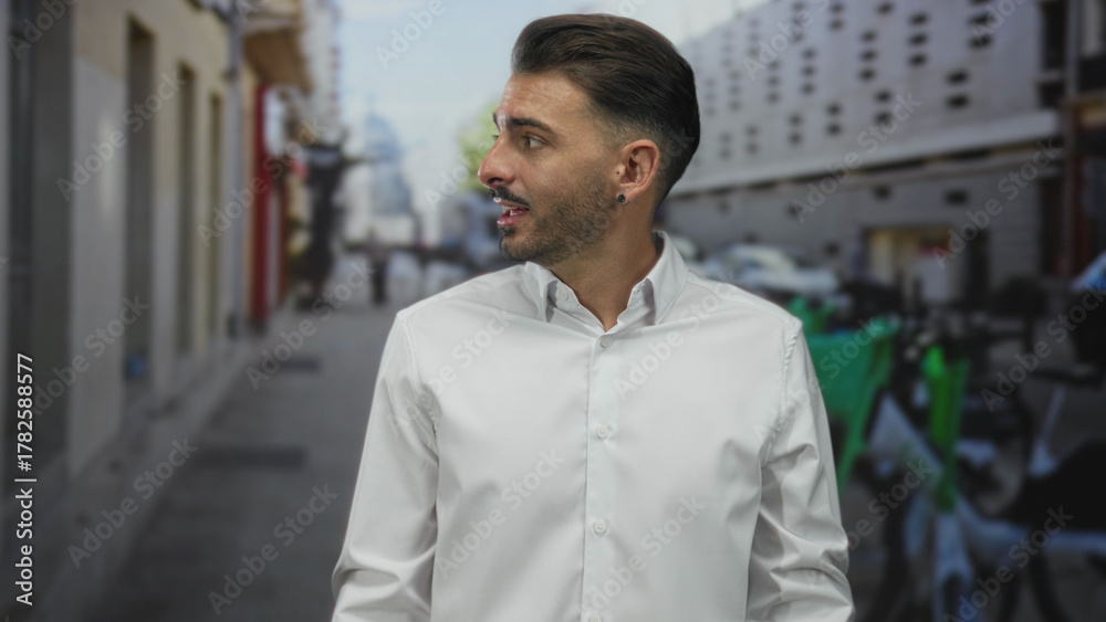 Obraz premium Man in white shirt shrugs shoulders on narrow crowded city street lined with parked scooters; uncertainty confusion.