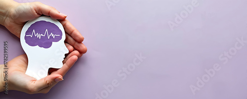Hands hold brain cutout. Paper head with encephalography on purple background. Alzheimer, autism awareness, stroke, epilepsy, ADHD, seizure disorder, mental health challenges concept. Support,