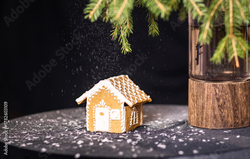 Christmas gingerbread house on black background with fir branches and snow