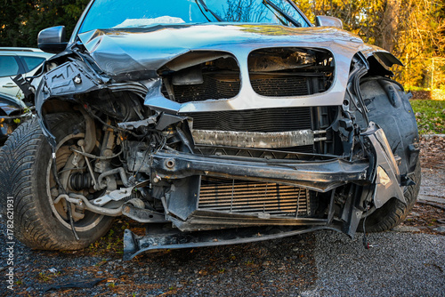 Heavily damaged car front end showing impact, bent metal, and ruptured radiator