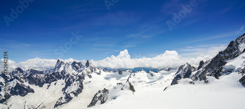 A view of a ridge of jagged, high, snow-covered mountains in the French Alps Photo taken from the Aiguille du Midi mountain Chamonix large snow cover with footprints is visible