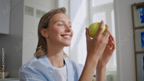 Photos Woman biting tasty apple in sunny kitchen