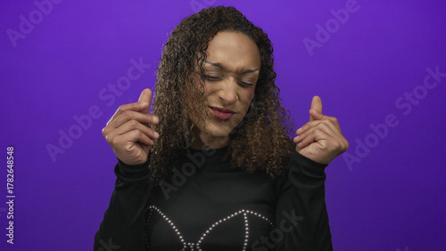 Bilde på lerret Transgender hispanic woman makes money gesture with fingers in a purple studio set; greed wealth desire