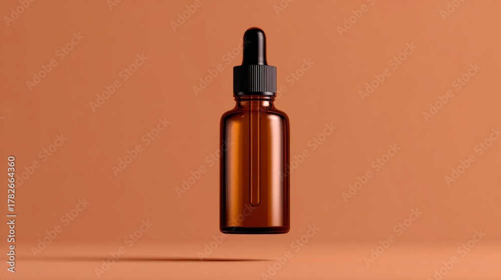 Fototapeta premium Minimalist studio shot of an amber glass dropper bottle floating against a warm terracotta background.