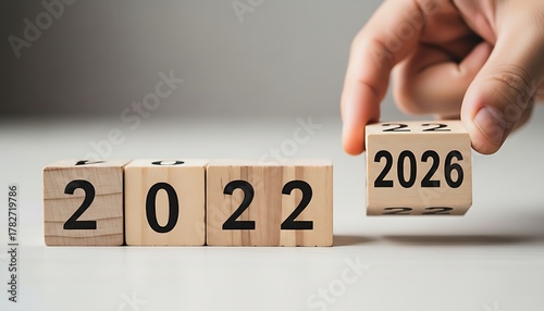 Hand changing wooden blocks from 2022 to 2026, representing future planning and change