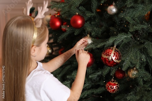 Little girl decorating Christmas tree at home