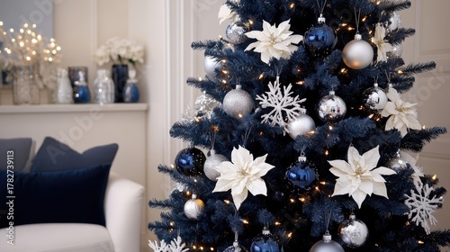 A beautifully decorated navy blue Christmas tree features shimmering silver and white ornaments, enhancing the festive atmosphere of the room