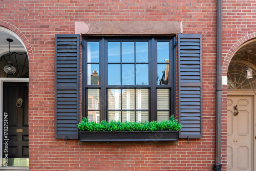Classic red brick facade with reflective window and decorative shutters in Beacon Hill, Boston, Massachusetts, USA
