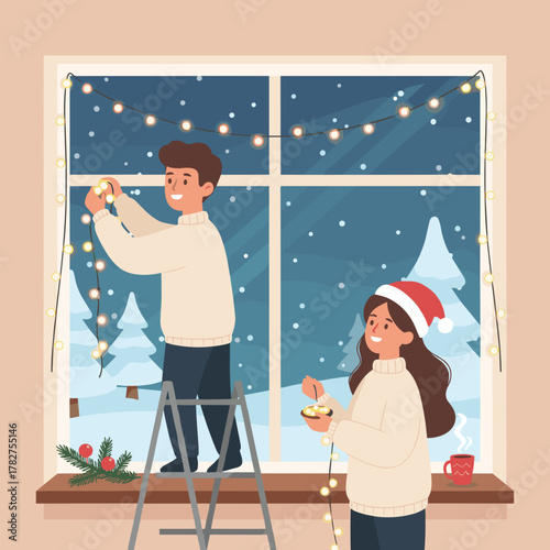Man and woman decorating window with Christmas lights and greenery  