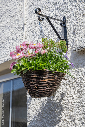 Wicker hanging flower basket on an old stucco building.
