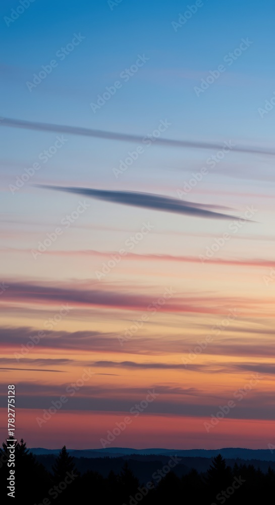 Fototapeta premium Dynamic long exposure view of soft blending clouds moving across a vast sky at twilight, creating a sense of smooth atmospheric flow ,smear ,dawn ,sunset