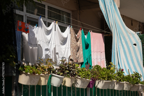 Papier peint Laundry hanging on a line above flower boxes on a sunny balcony in Istanbul, Tur