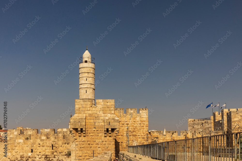Fototapeta premium jerusalem, Israel, 9 October 2025, The historical tower of david (phasa'el tower) and the old city walls made of jerusalem stone, standing against a clear, bright blue sky in the daytime.