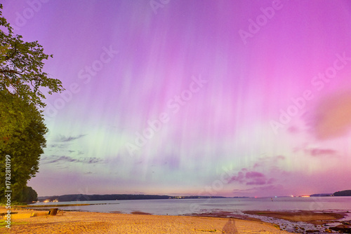 Fototapeta Naklejka Na Ścianę i Meble -  Rare northern lights over Flensburg Baltic Sea beach glowing in pink and green night sky