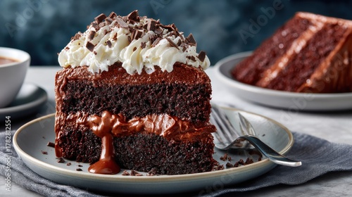 A slice of rich chocolate cake with whipped cream, chocolate shavings, and sauce on a plate